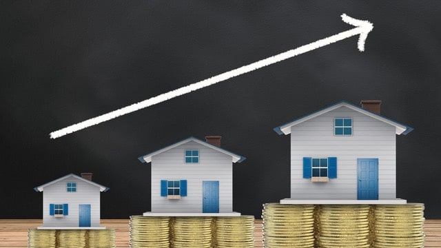 Three houses on increasing stacks of coins with an upward trending arrow, symbolizing the growth in scaling your real estate portfolio