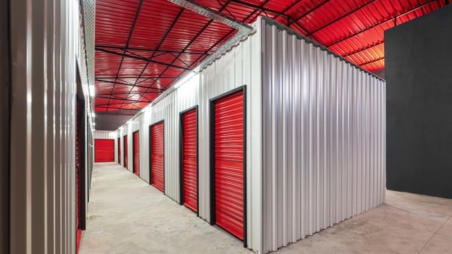 Interior view of a modern self-storage facility with red doors and metal walls, illustrating self-storage investments.