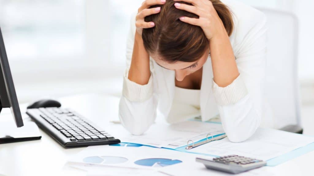 Frustrated woman at a desk with paperwork, symbolizing the stress of a property manager switch, as she considers changing management for better service